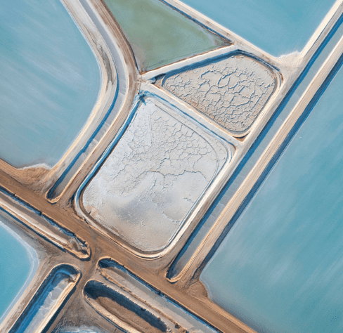 An aerial view of light blue and white salt mines or salt pools