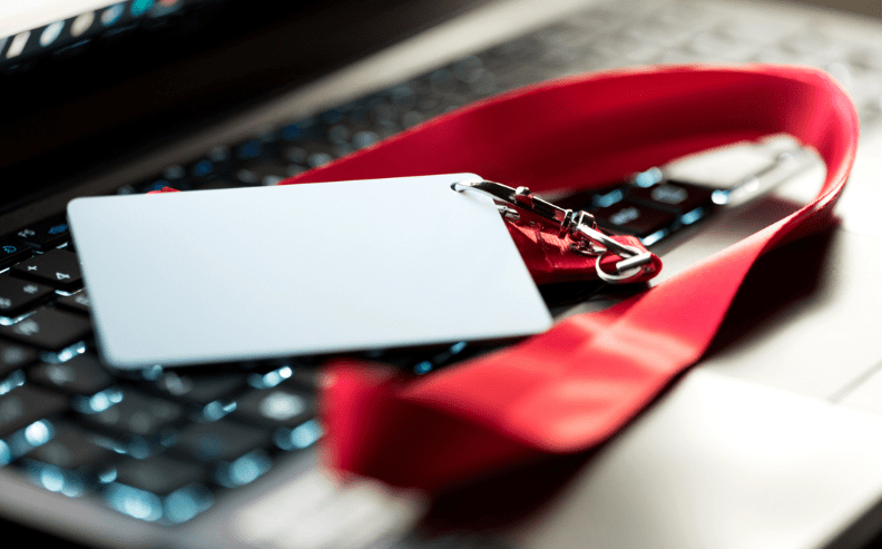 A blank ID badge with a red lanyard lies on a laptop keyboard.