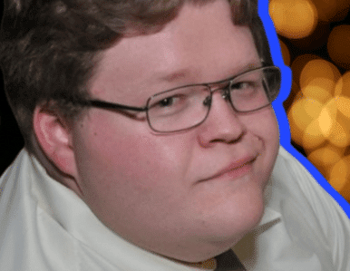 A person with short light brown hair and glasses is wearing a white shirt, looking at the camera with a slight smile. The background is blurred with yellow lights and a blue outline around the person.