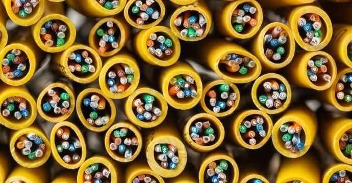 Close-up view of numerous yellow cables, each showing multicolored wires inside, arranged in a tightly packed, organized pattern with the open ends facing the viewer.