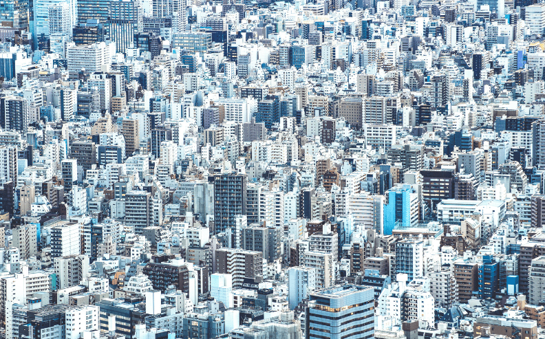 A dense cityscape filled with closely packed high-rise buildings and skyscrapers, creating an urban jungle effect under bright daylight.