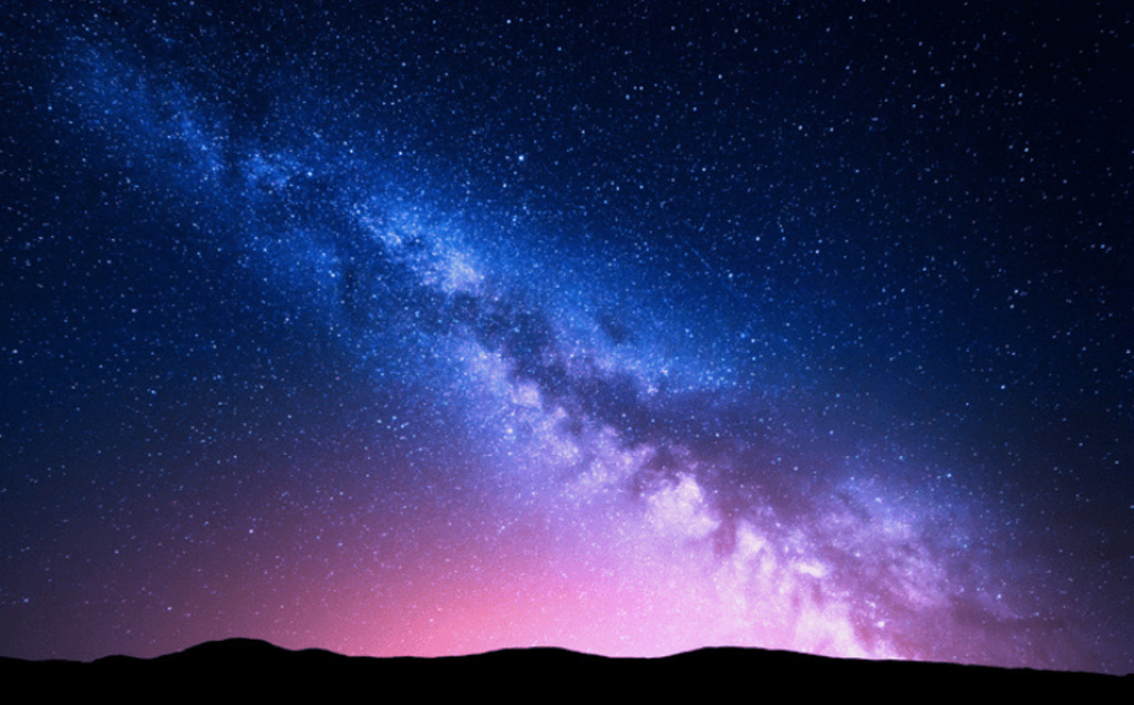 A vibrant night sky filled with stars and the Milky Way stretching diagonally above a dark, silhouetted landscape, with a purple and pink glow on the horizon—reflecting Identity Data Fabric’s value impact as defined by Radiant Logic’s approach.