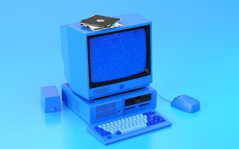 A vintage desktop computer in blue with a CRT monitor showing static, a keyboard, a mouse, and floppy disks on top, all set against a blue background.