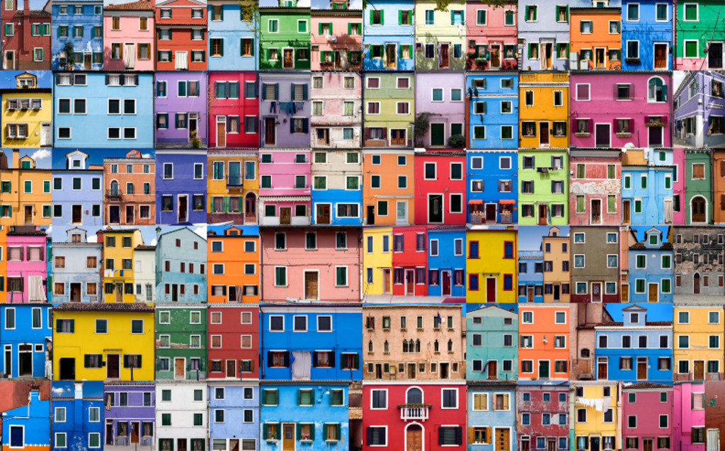 Colorful rows of buildings with various shapes and sizes, each painted in vibrant hues like blue, yellow, pink, orange, green, and purple, creating a lively mosaic of facades with windows and doors.