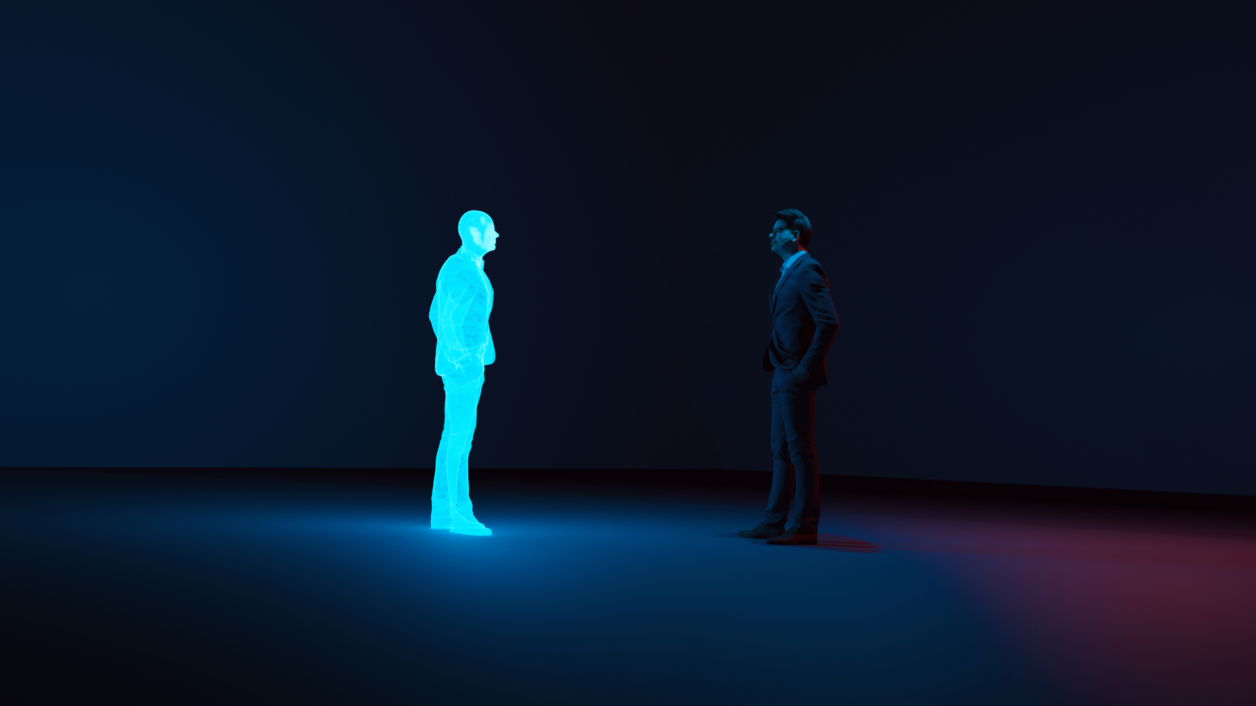 A man in a suit stands in a dark room facing a glowing blue holographic figure of a person. Blue and red lights cast contrasting glows on the floor, emphasizing the futuristic and surreal atmosphere.