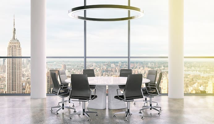 A modern conference room with a round table, eight black office chairs, large windows, city skyline view, and a circular ceiling light. The Empire State Building is visible outside.